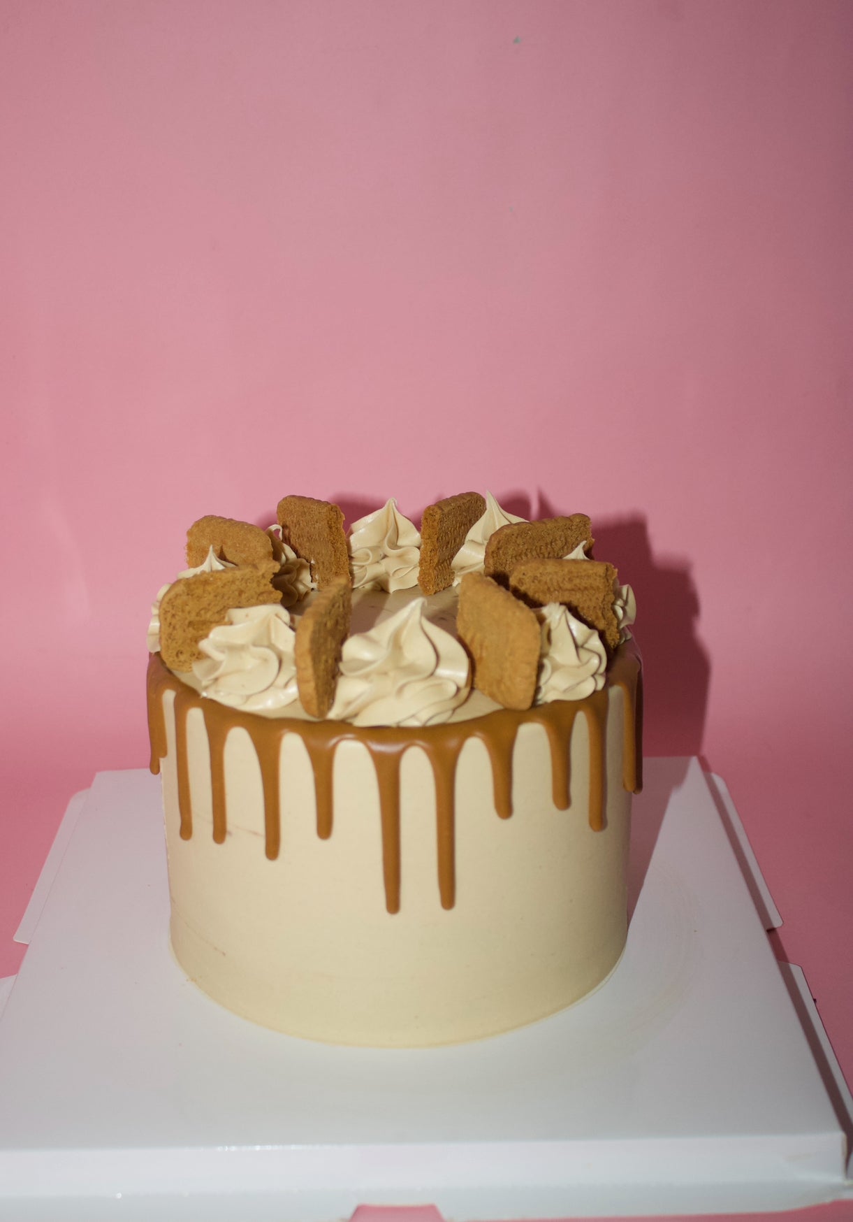 Biscoff drip cake topped with cream swirls and Biscoff biscuits