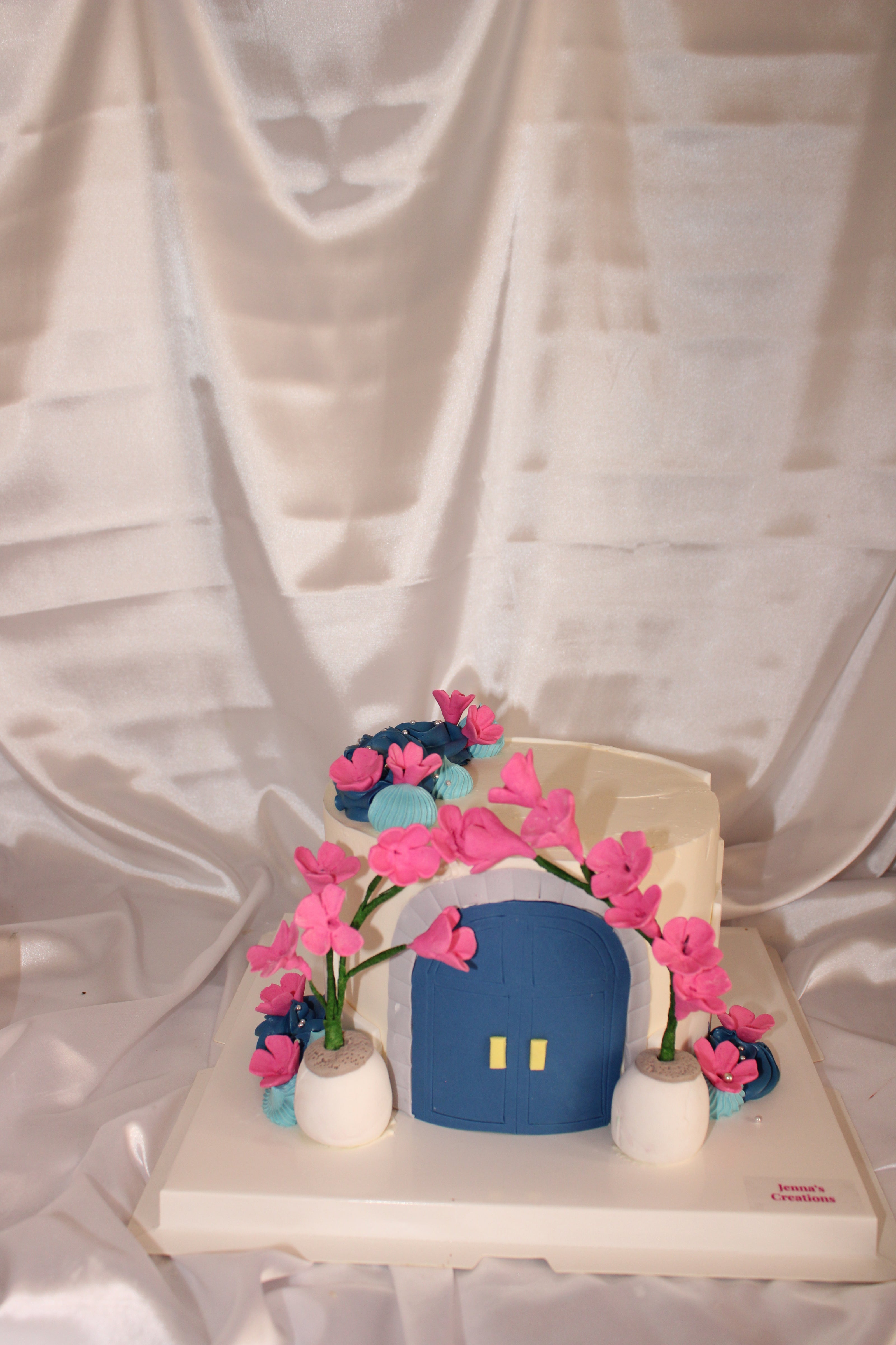Decorative wall piece with a blue square and pink flowers on a white background