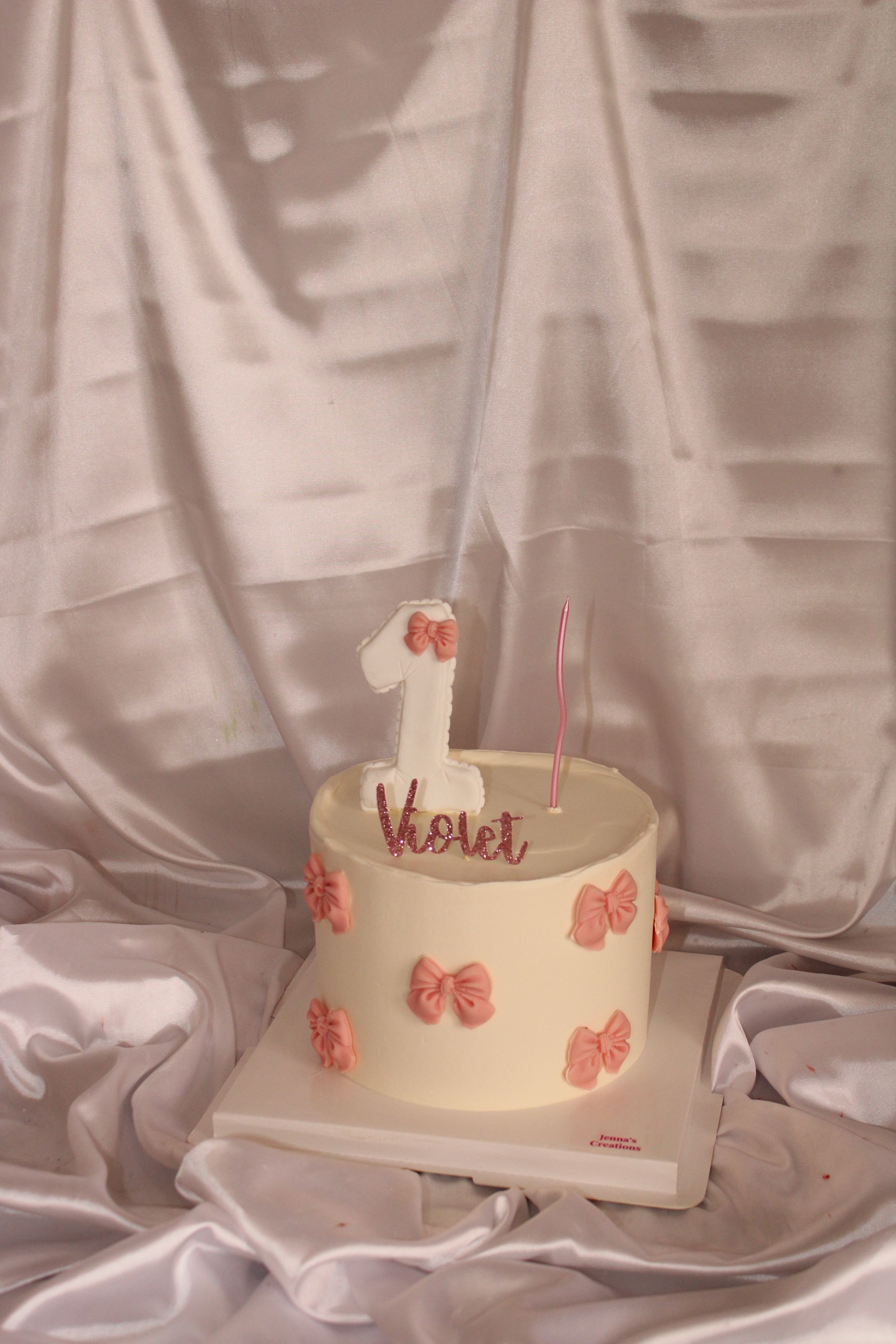 Small cake with a number one candle on a white surface with a gray fabric background