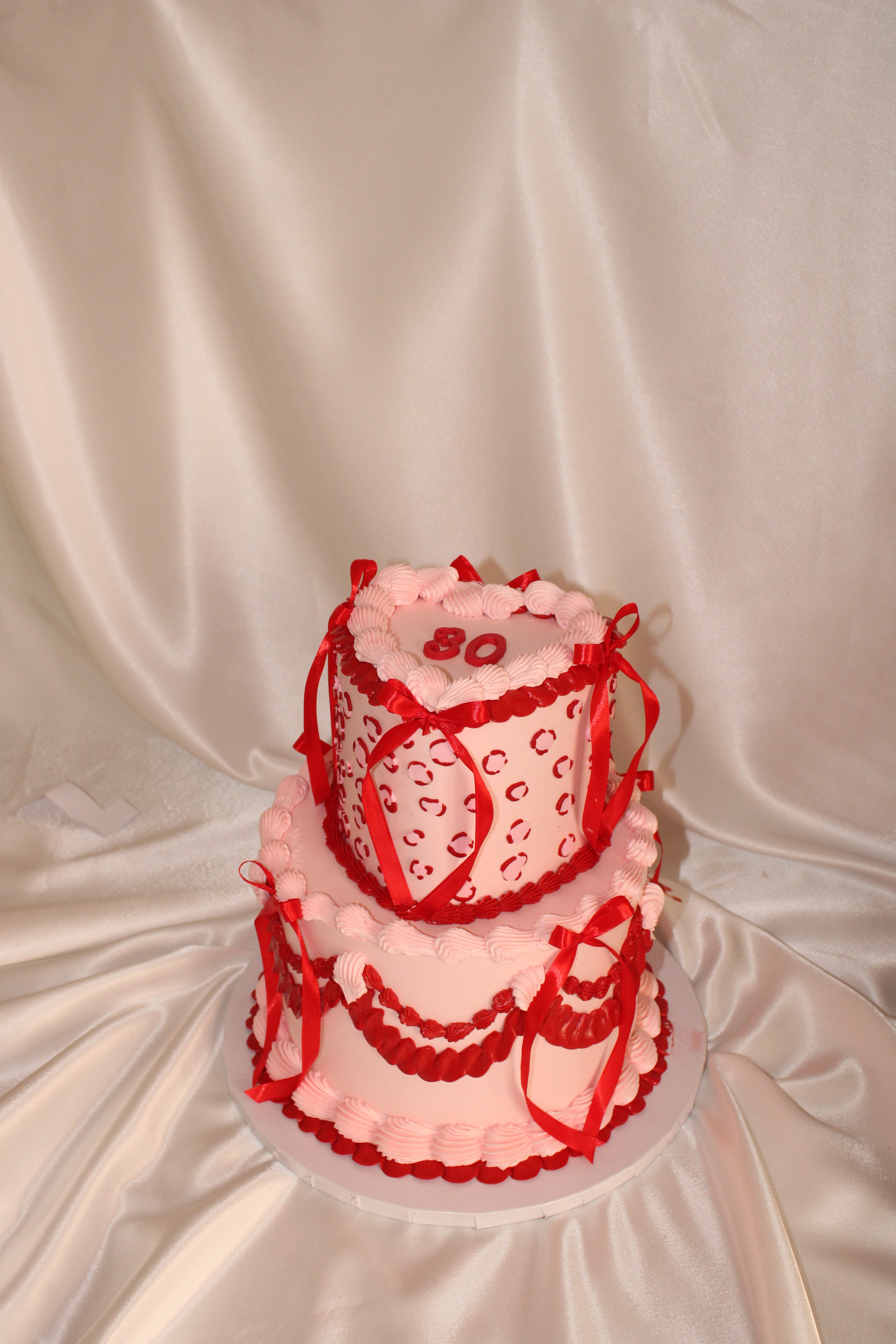 Three-tiered cake with red and white decorations on a white background
