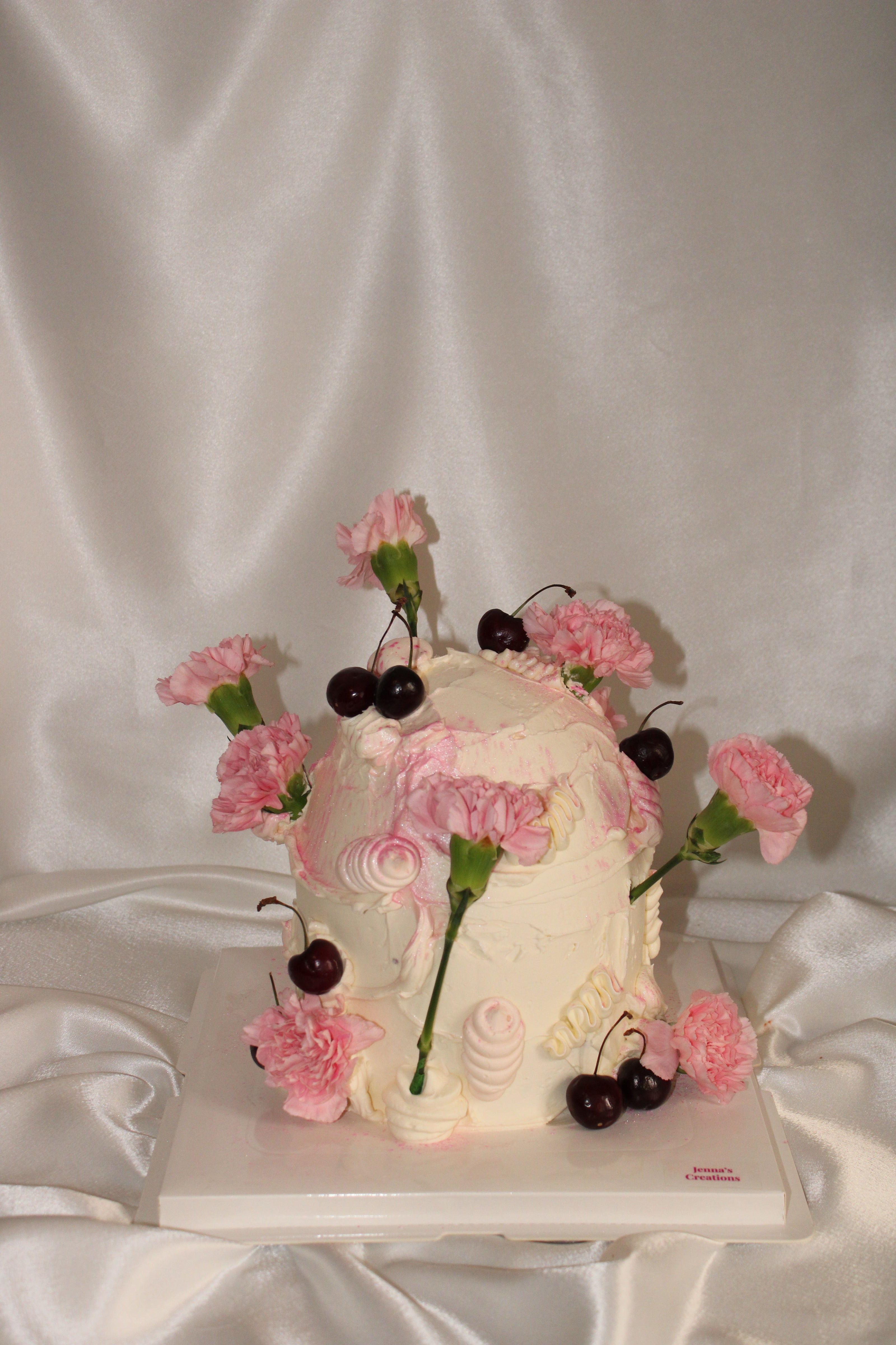Decorative cake shaped like the number '9' with pink flowers and cherries on a white background