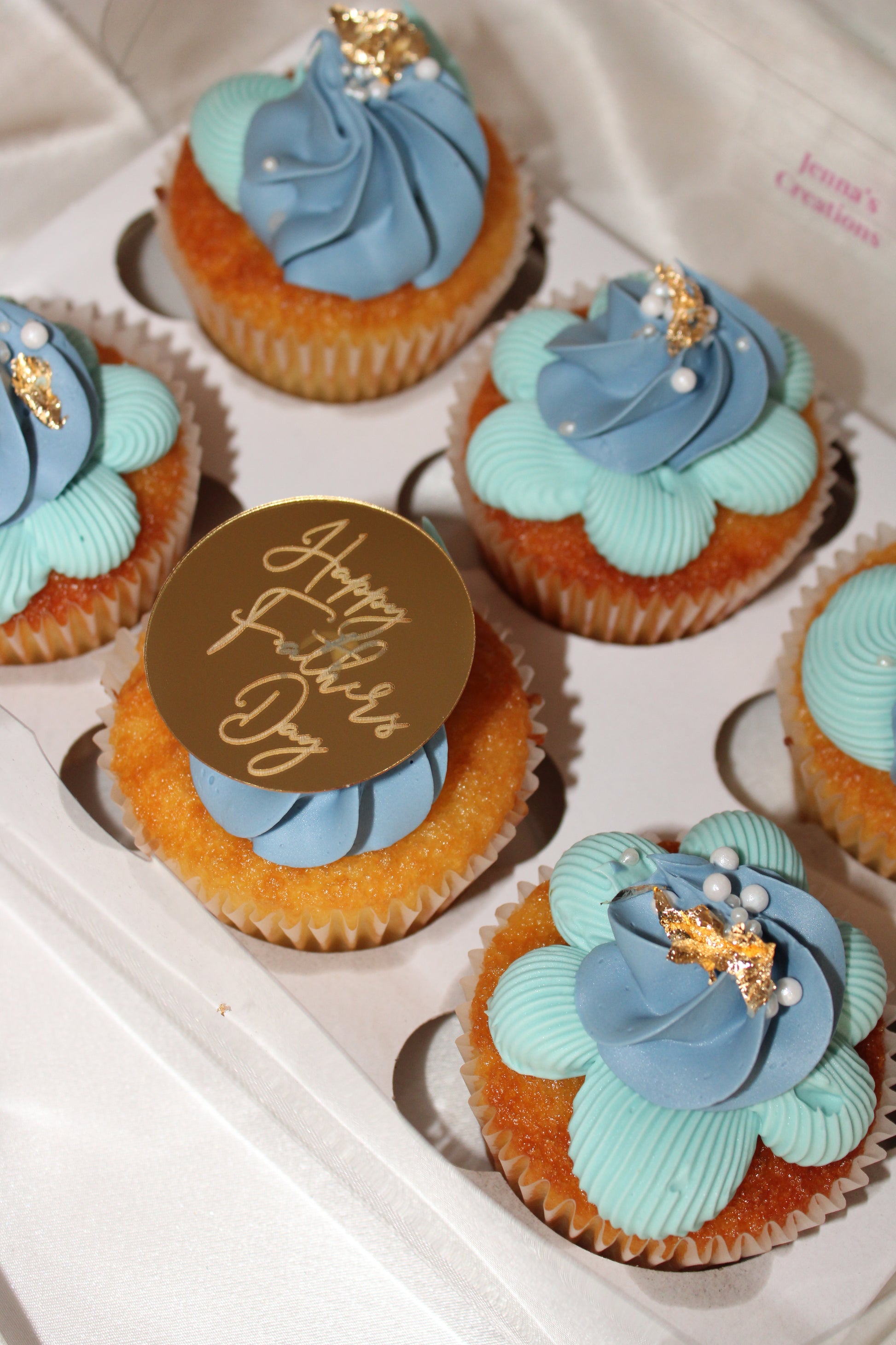 Six gourmet vanilla cupcakes with blue buttercream rosettes and Happy Father’s Day decoration.