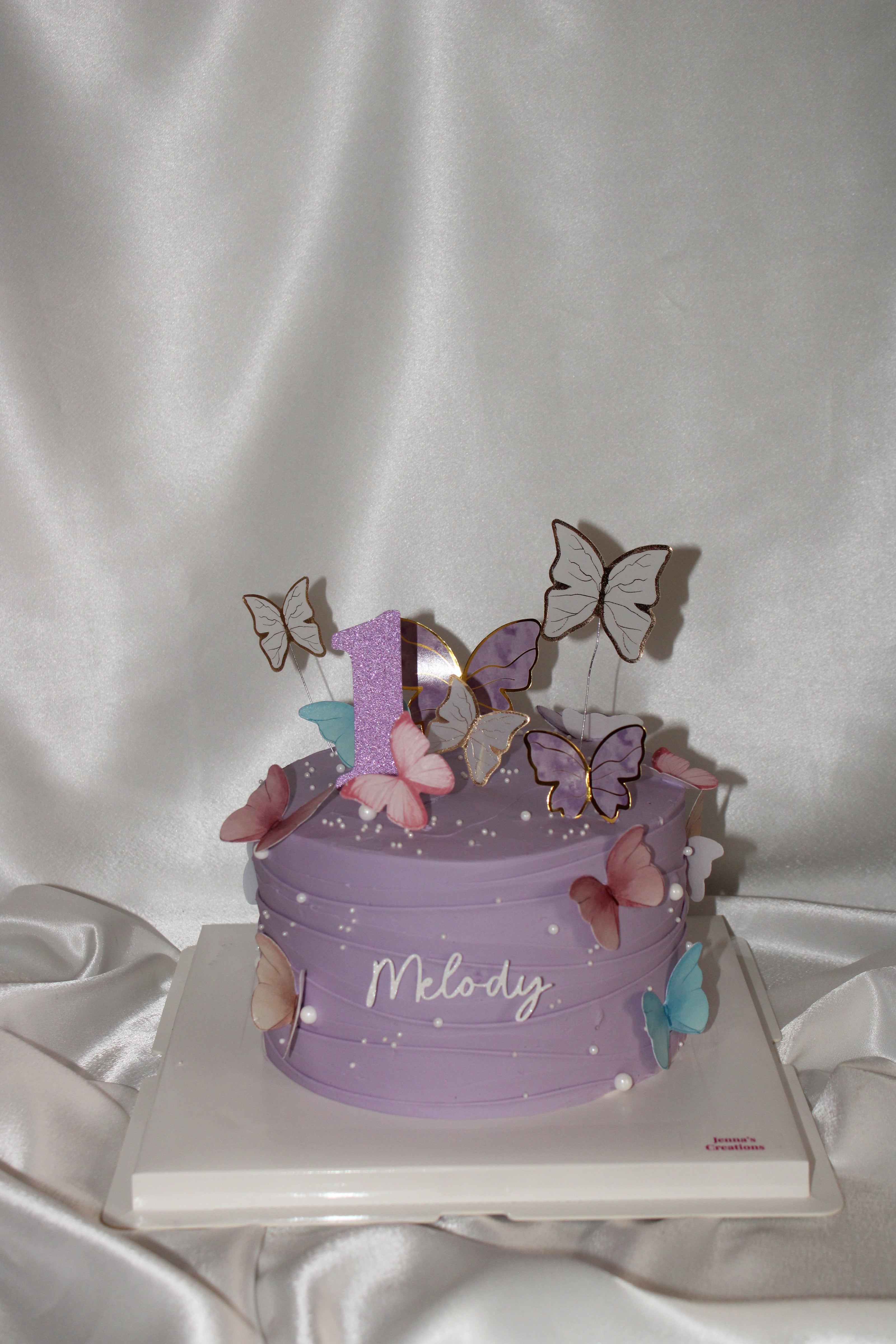 Purple birthday cake with butterfly decorations on a white background