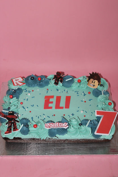 Decorative cake with blue frosting, red letters, and cartoon character on a pink background