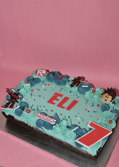 Birthday cake with 'ELI' and 'Roblox' decorations on a pink background