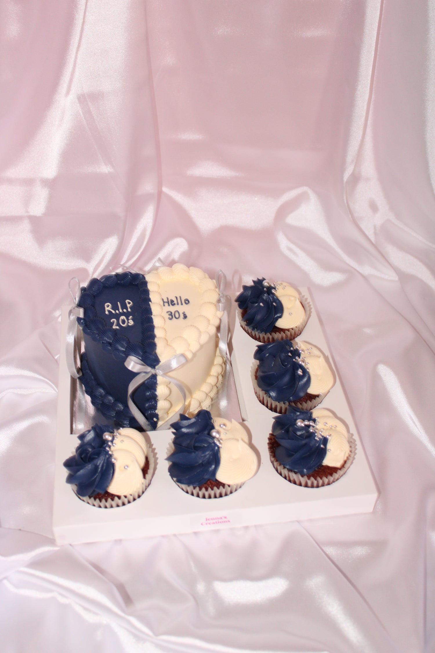 Cupcakes with blue and white frosting in a box on a pink background