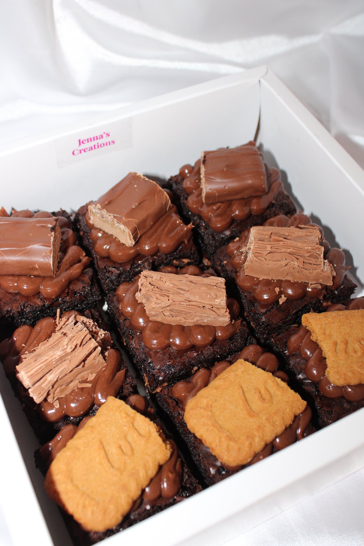 Rich fudgy brownies with a variety of toppings including chocolate chunks and biscuits, presented in a gift box