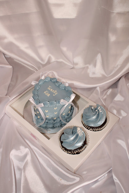 Decorative blue cupcakes in a box on a satin surface