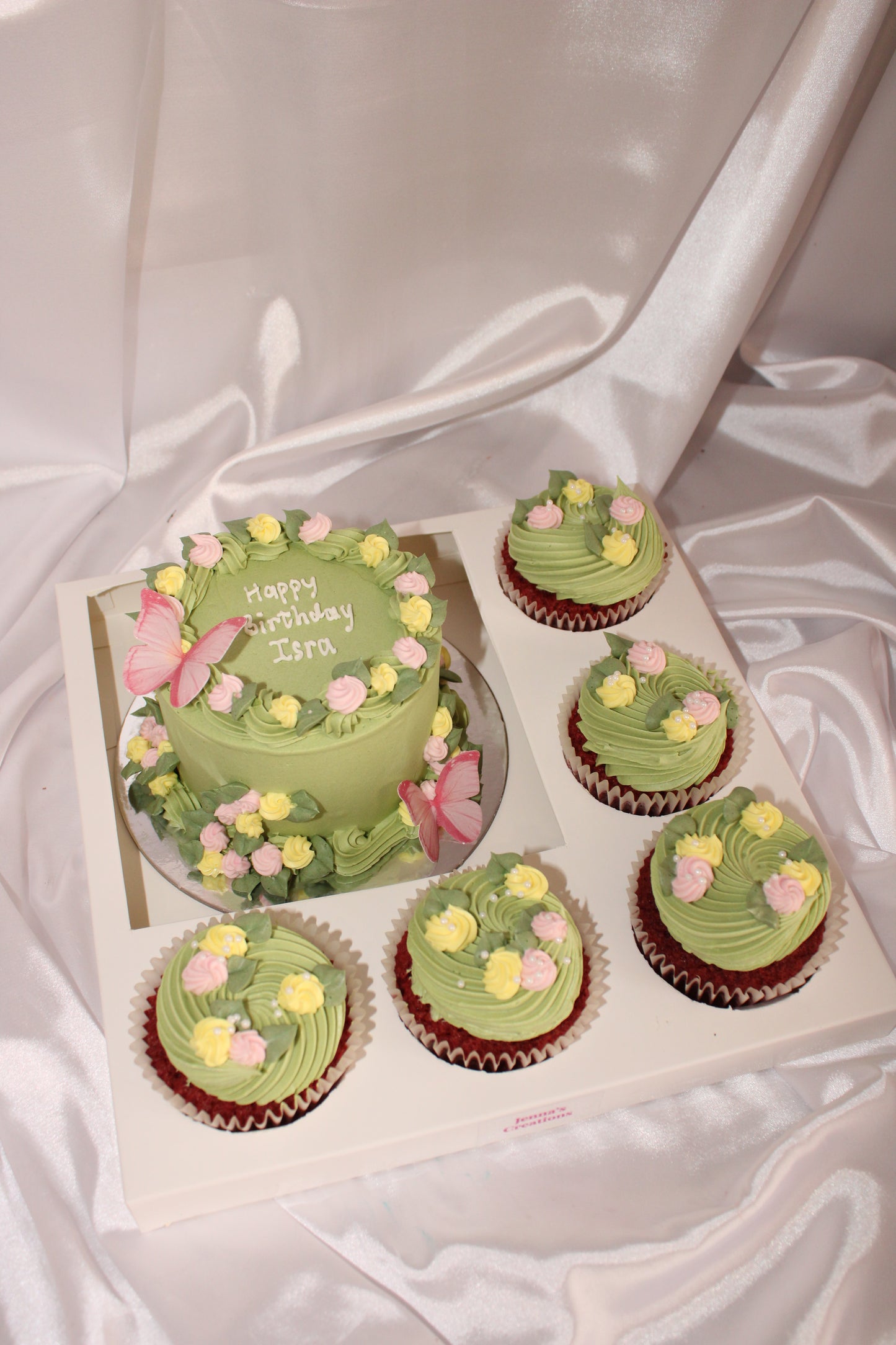 Green cupcakes and a cake with floral decorations on a white surface
