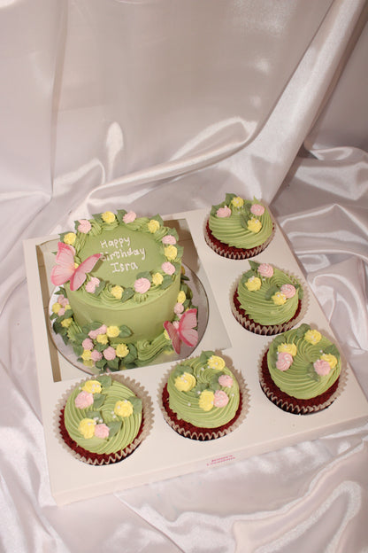 Green cupcakes and a cake with floral decorations on a white surface