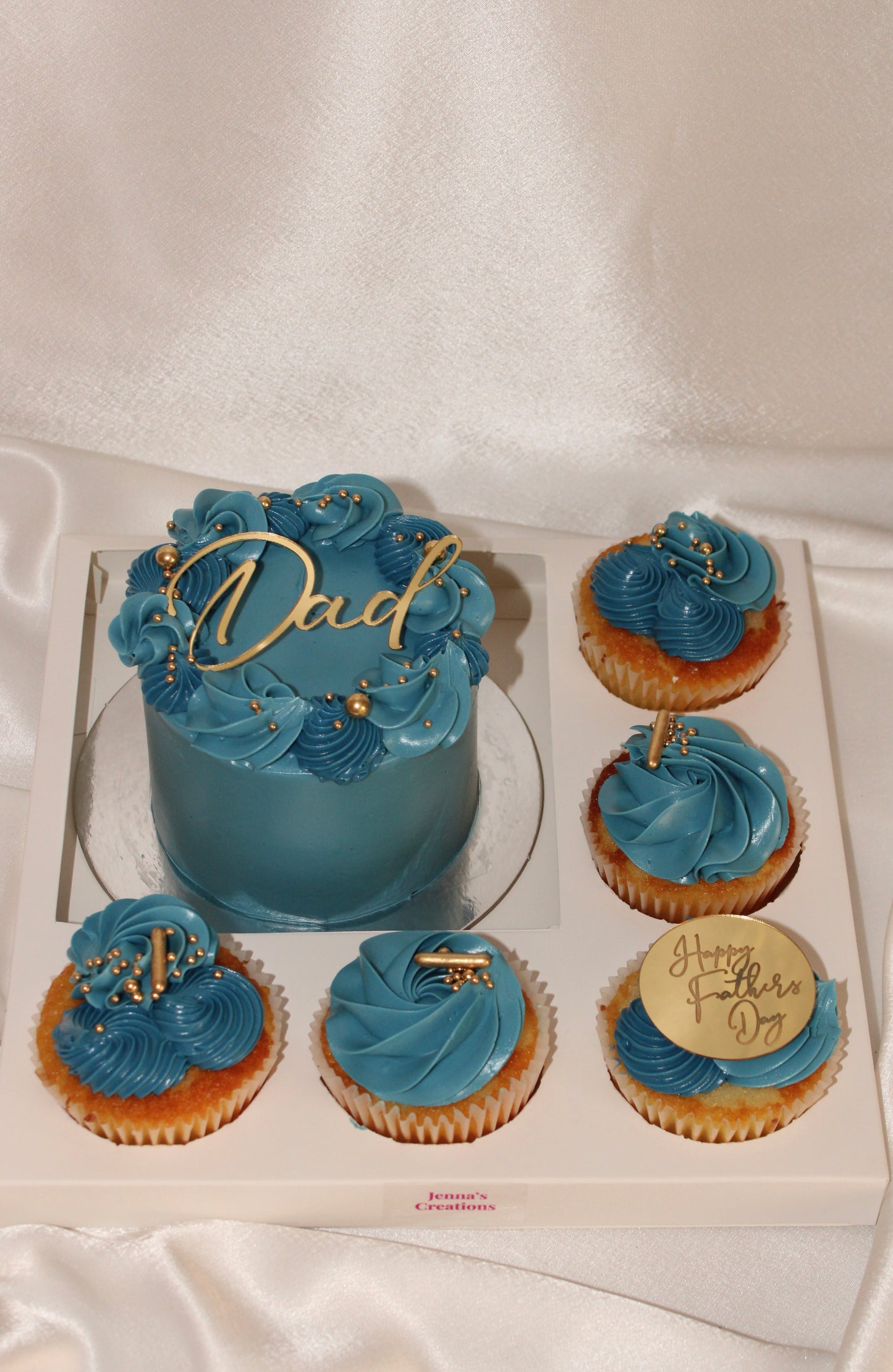 Father’s Day gift box with a blue buttercream mini cake and six matching cupcakes decorated with gold accents.