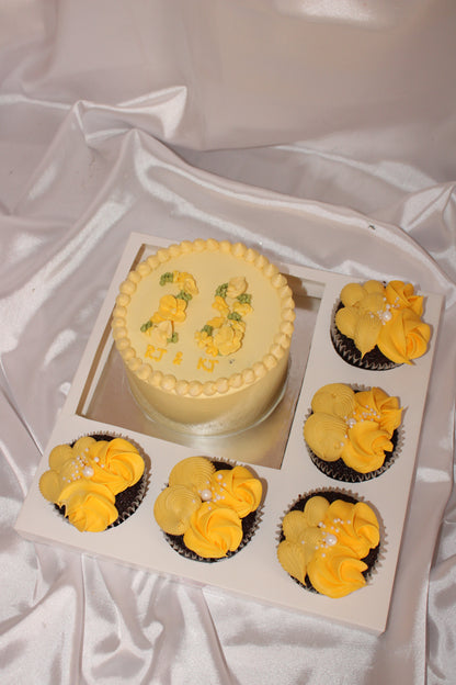 Decorative cake and cupcakes with yellow flower toppings on a white surface