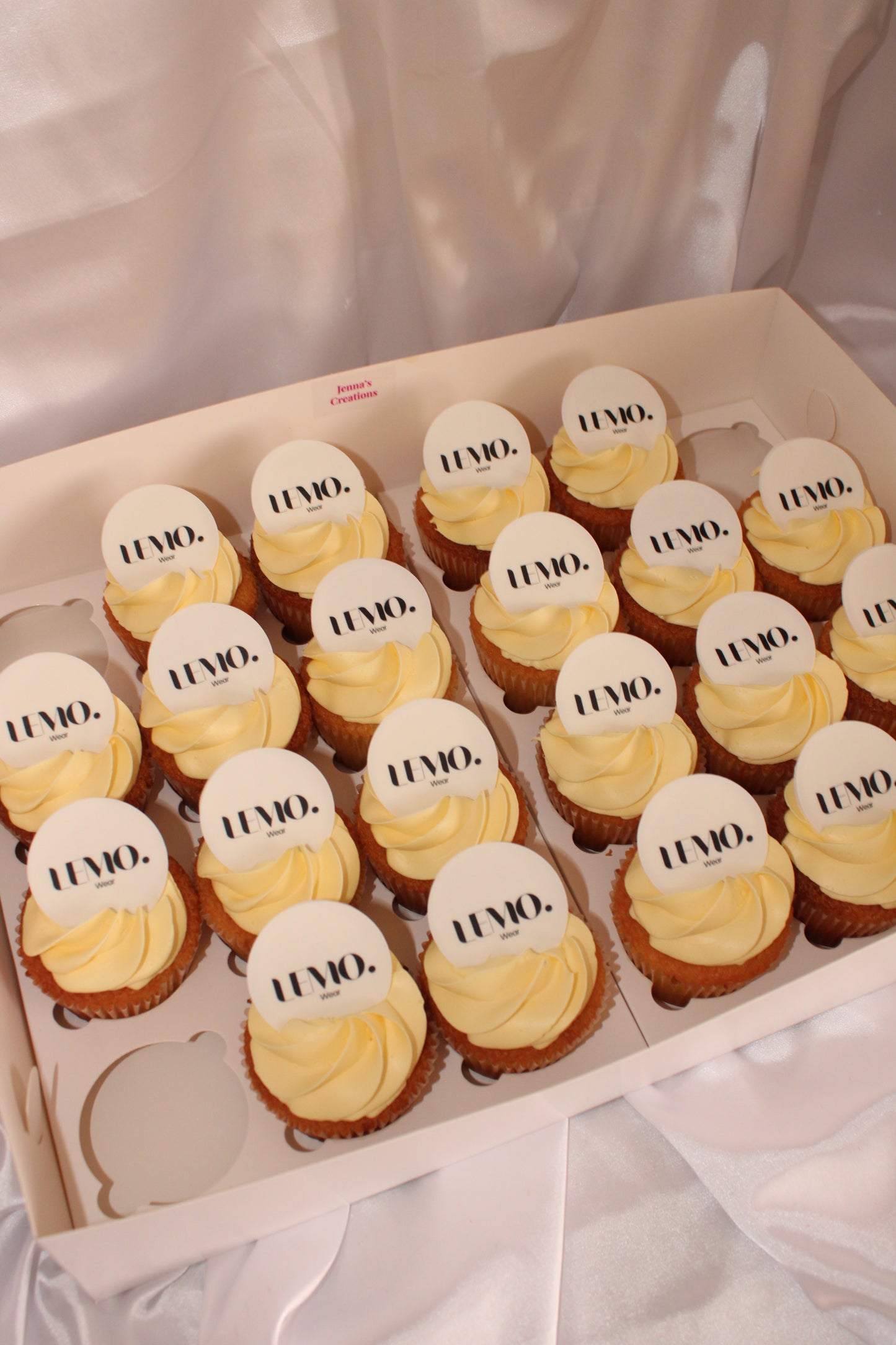 Close-up of frosted cupcakes featuring custom printed company logos on edible toppers.