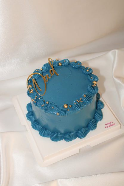Elegant blue celebration cake featuring piped buttercream borders and a gold Dad cake topper.