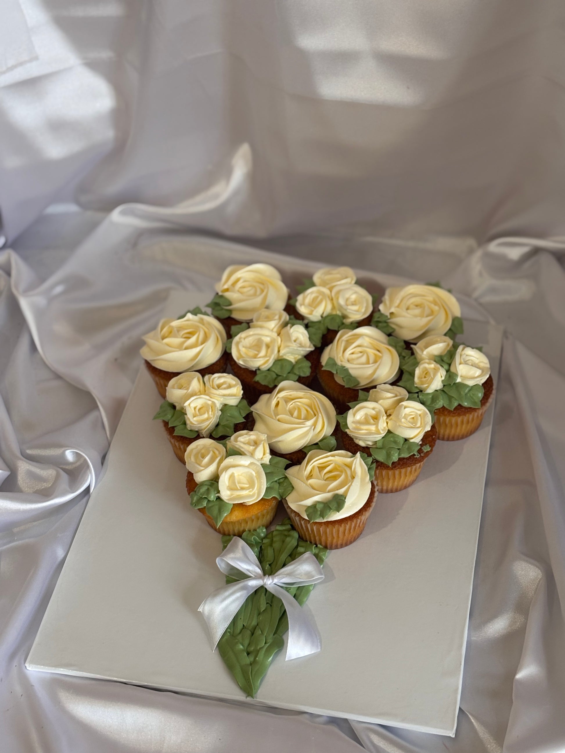 Floral cupcake bouquet featuring white buttercream roses with a satin bow