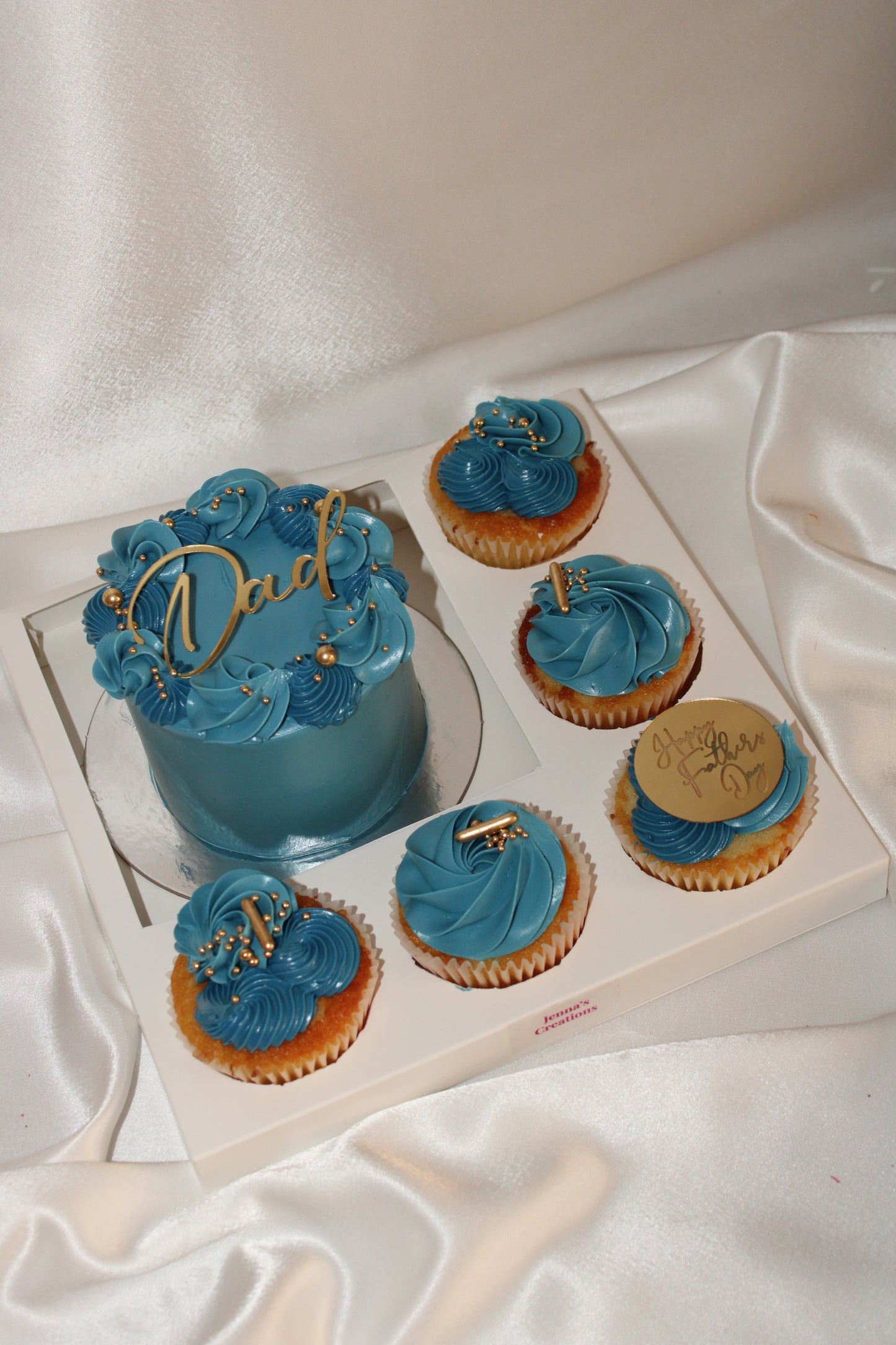 Elegant blue and gold Father’s Day cake and cupcake set featuring a “Dad” topper and decorative buttercream swirls.