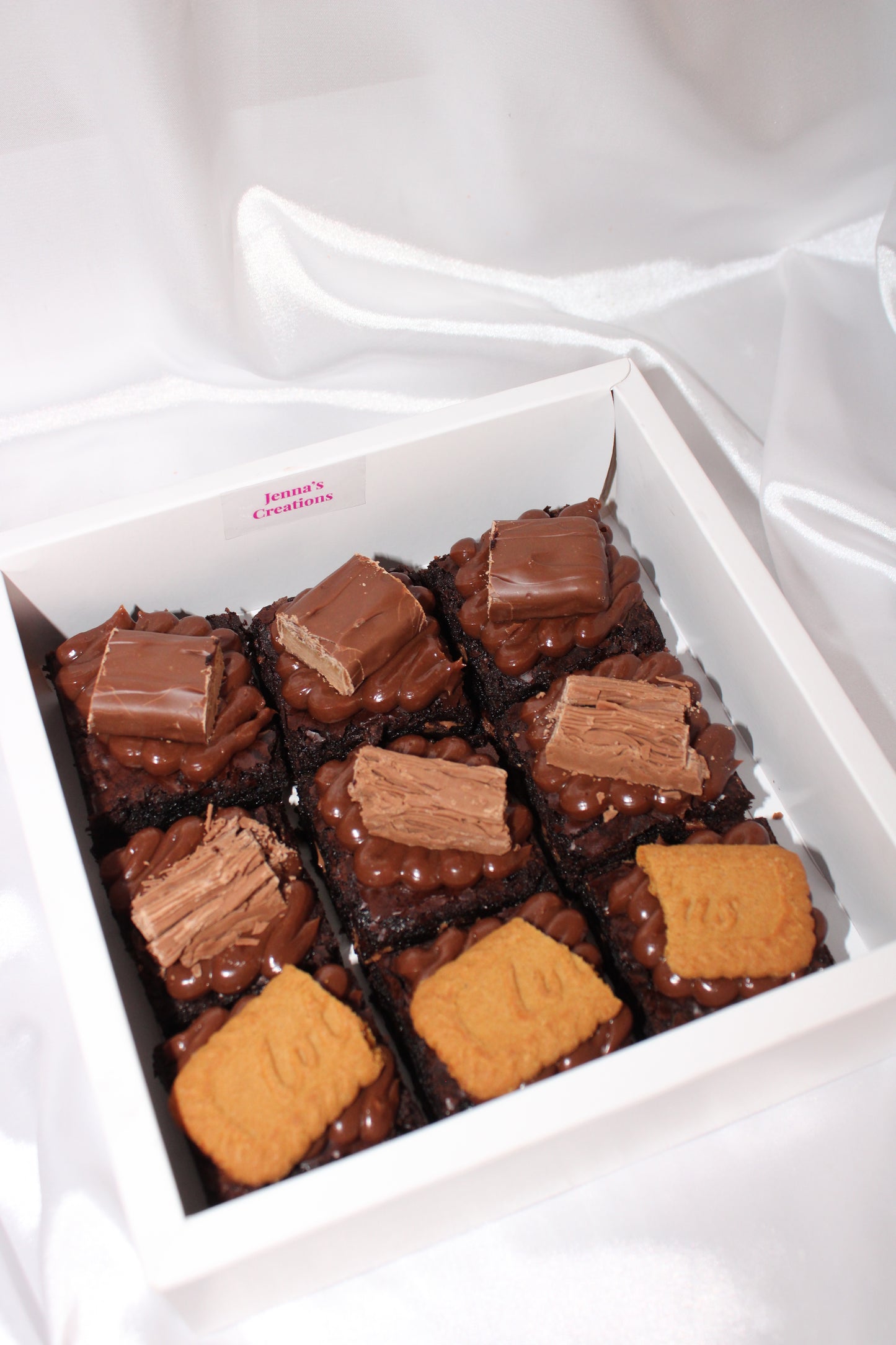 Homemade brownie squares decorated with different chocolate toppings and cookies in a white tray