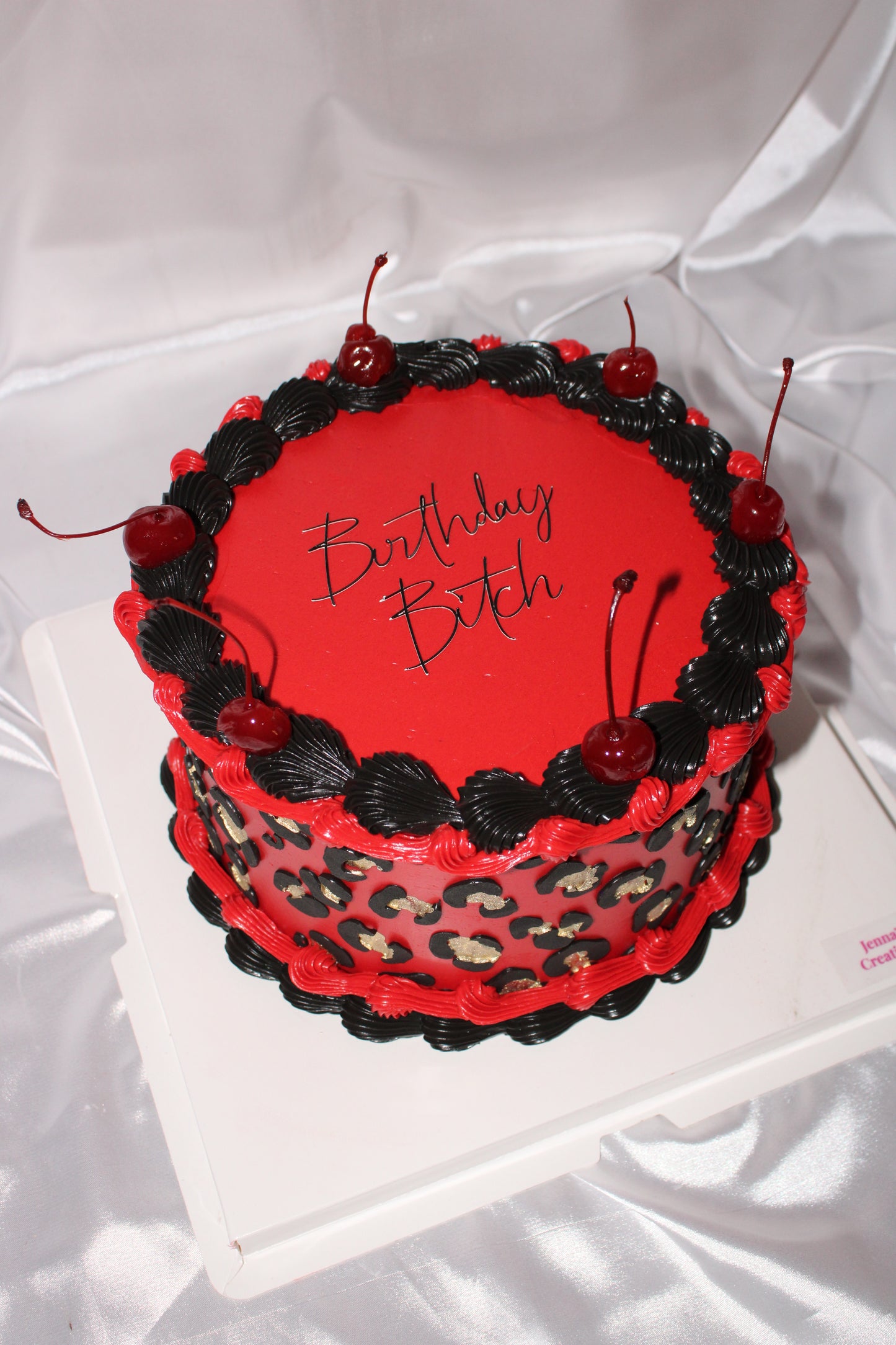 Cherry decorated birthday cake with gold leopard print accents.