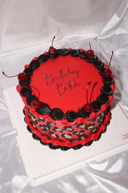 Cherry decorated birthday cake with gold leopard print accents.