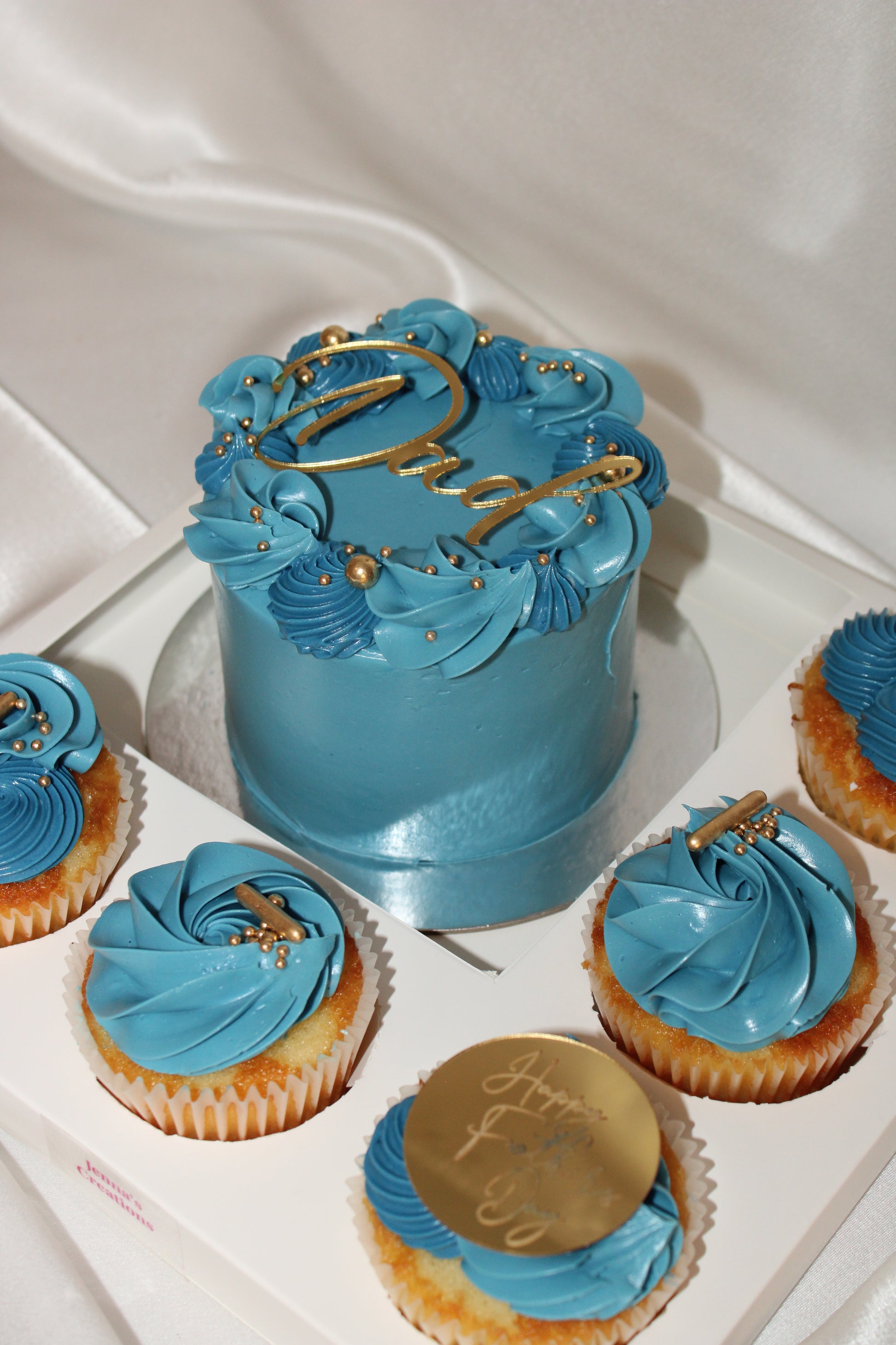 Mini blue celebration cake surrounded by six coordinating cupcakes in a premium Father’s Day gift box.