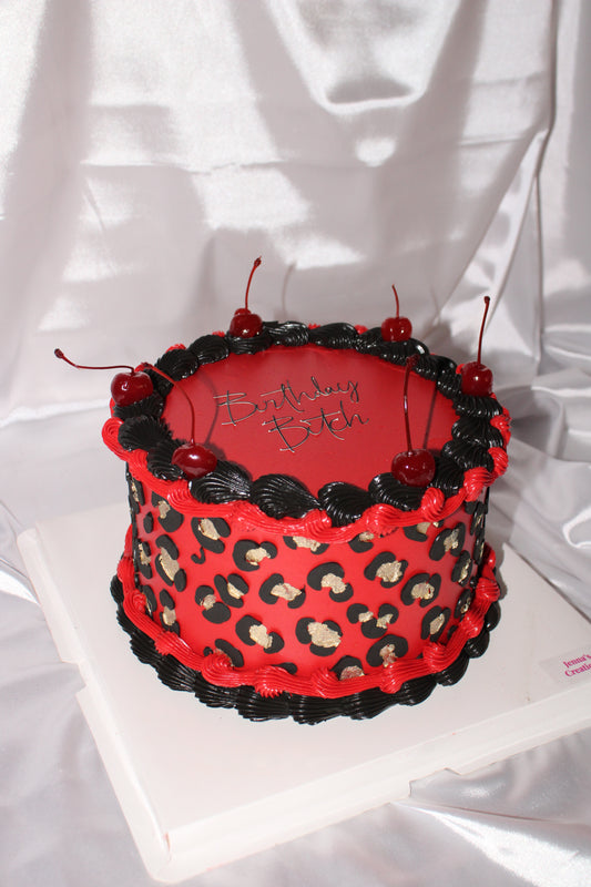 Luxury red birthday cake with leopard print sides and buttercream piping.