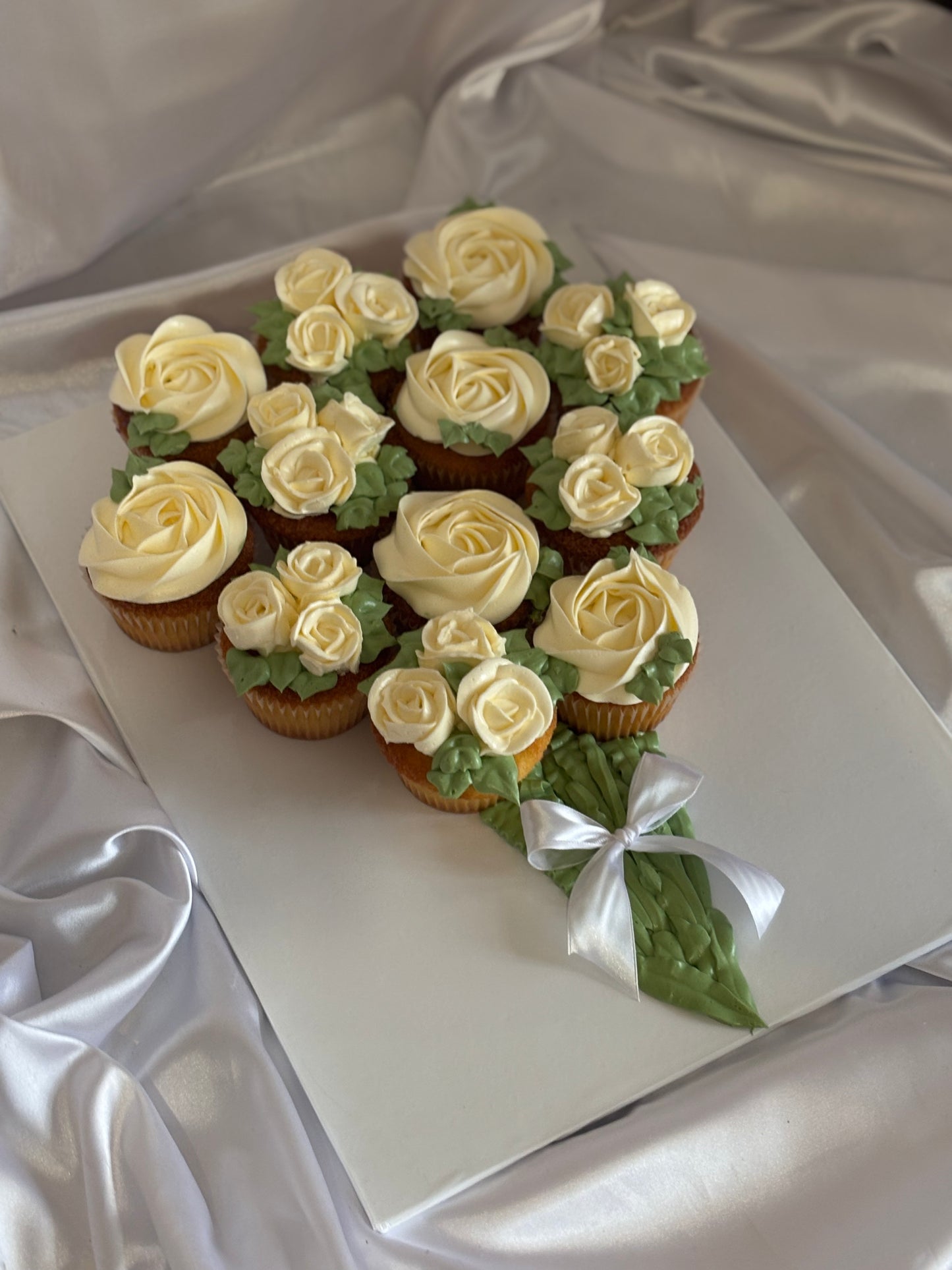Elegant cupcake bouquet decorated with buttercream roses and green leaves